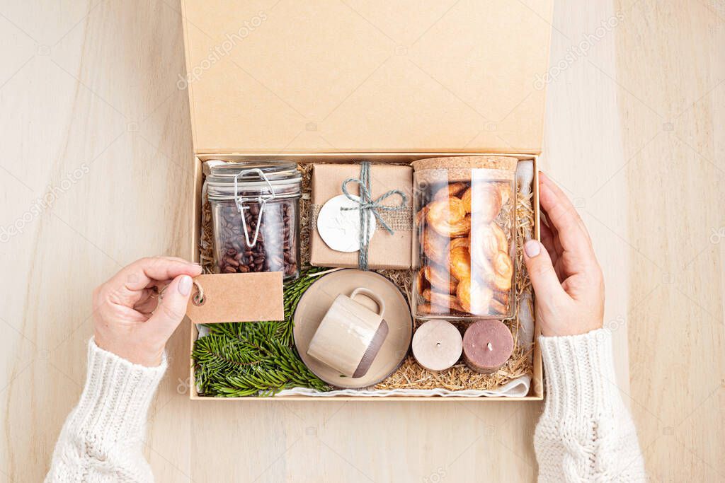 Preparing care package, seasonal gift box with coffee, cookies, candles and cup. Personalized eco friendly basket for family and friends for thankgiving, christmas, mothers and fathers day holidays. 