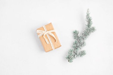 Noel ağacı dalı ve hediye kutusu beyaz arka planda organik el sanatları kağıdına sarılı, düz, üst manzara, kopyalama alanı. Kış tatili, xmas tebrik kartı.