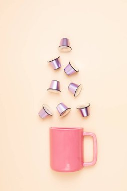 Kahve kapsüllerinin üst görüntüsü ve bej arka planda fotokopi alanı olan fincanlar. Sabah dozunda kafein, enerji, lezzet konsepti. Model, düz yat.