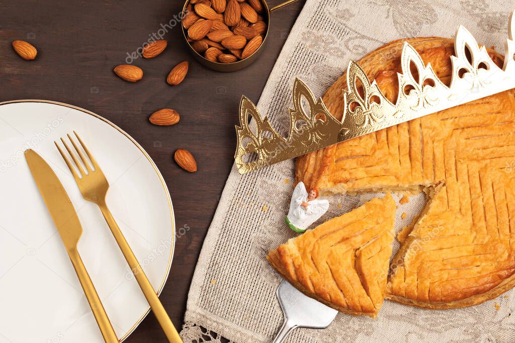 King cake or galette des rois in French. Traditional epiphany pie with golden paper crown and tiny charms. Top view, flat lay