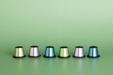 Yeşil arka planda fotokopi alanı olan tek kullanımlık kahve kapsülleri. Sabah dozunda kafein, enerji, lezzet konsepti. Mockup, boşluğu kopyala