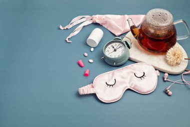 Klasik çalar saat, uyku maskesi, haplar ve bitki çayı. Asgari dinlenme konsepti, uyku kalitesi, iyi geceler, uykusuzluk, rahatlama. 