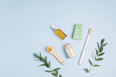 Kozmetik markalaşma modeli. Gerekli yağ şişeleri, deniz tuzu, sabun çubuğu, mavi arka planda taze okaliptüs dalları. Cilt bakımı, vücut bakımı, güzellik ürünü konsepti için doğal organik malzemeler. Düz yatıyordu