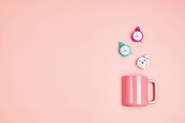 Pastel arka planda alarmlı pembe bardak. Sabah, çay ya da kahve zamanı, rahatlama konsepti. Üst görünüm, düz görünüm, kopyalama alanı olan maket