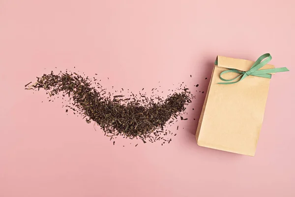 乾燥した緑茶の葉およびピンクの背景の紙袋 環境に優しいオーガニックブランドのコンセプト ブランドのモックアップ フラットレイアウト トップビュー — ストック写真