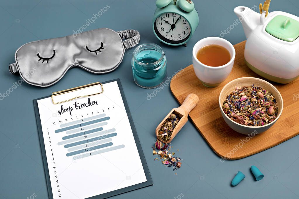 Classic alarm clock, sleeping mask, sleep tracker and herbal tea on blue background.  Minimal concept of rest, quality of sleep, good night, insomnia, relaxation. Copy space