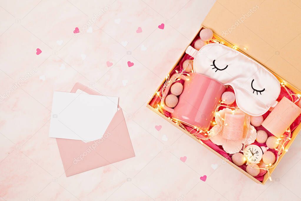 Preparing care package, seasonal gift box with tea cup, candles and sleeping mask. Personalized eco friendly basket for saint valentine, mothers day. Top view, flat lay, mock up