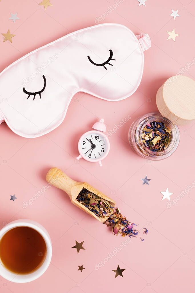 Classic alarm clock, sleeping mask and herbal tea.  Minimal concept of rest, quality of sleep, good night, insomnia, relaxation. Copy space