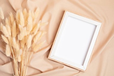 Bej kumaş arkaplanı üzerine boş çerçeve kurutulmuş çimen modeliName