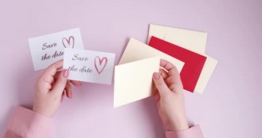 Kadın eli zarfa tarih kartını koyuyor. Düğün planlaması, davetiye konsepti