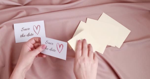 여자 손으로 날짜 카드를 봉투 안에 넣어 둔다. 결혼 계획, 초대 개념 — 비디오