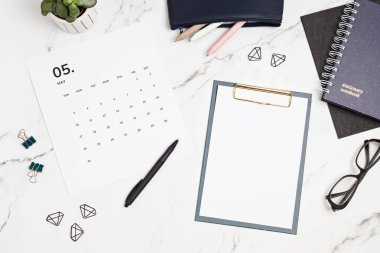 Mayıs ve ofis malzemeleri için takvimi olan bir masaüstü. Ev ofisi, sosyal medya blogu, program, planlama konsepti. Flatlay, üst görünüm