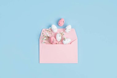 Mavi arka planda paskalya yumurtaları olan pembe bir zarf. Paskalya bayramı tebrik kartı kavramı