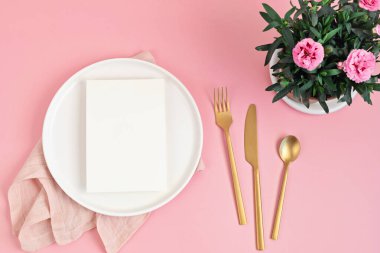 Mönü ve bahar çiçekleriyle yatıyordu. Pembe arka planda beyaz plaka. Kutlama, şenlikli yemek daveti fikri