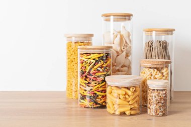 Tahta masadaki cam kavanozlarda geleneksel İtalyan makarnası çeşitleri. Sağlıklı dengeli gıda, sürdürülebilir yaşam tarzı, sıfır atık çevre dostu kavram.