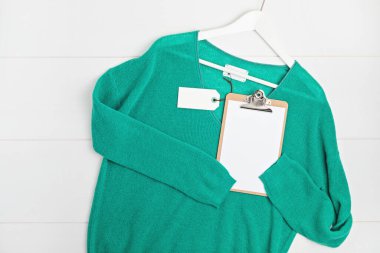 İkinci el kıyafet fikri. Dairesel fshion, çevre dostu sürdürülebilir alışveriş, dükkan konsepti. Etiket modeliyle kazağın üstünü göster.