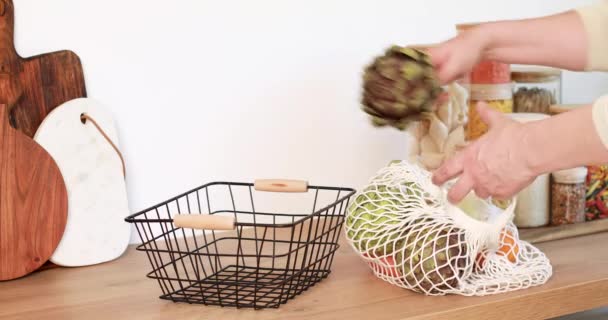 Mujer sacando verduras de la bolsa de malla, poniéndolas en la cesta. Productos reutilizables, cero residuos — Vídeos de Stock