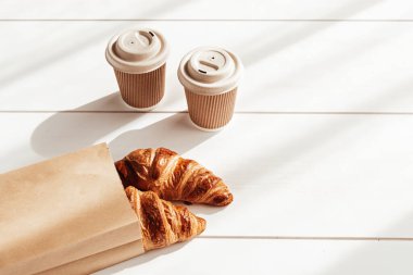 Sıcak kahve ve kahvaltıda kruvasan. Biyolojik ayrıştırılabilir, tek kullanımlık bardaklar.