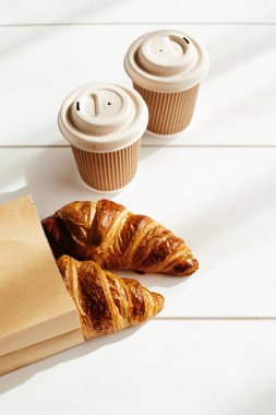Hot coffee on the go and croissants for breakfast. Biodegradable, disposable takeaway cups clipart