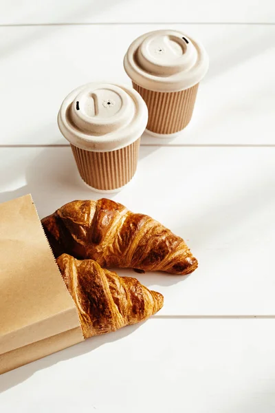 Hot coffee on the go and croissants for breakfast. Biodegradable, disposable takeaway cups — Stock Photo, Image