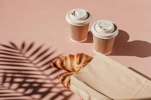 Hot coffee on the go and croissants for breakfast. Biodegradable, disposable takeaway cups