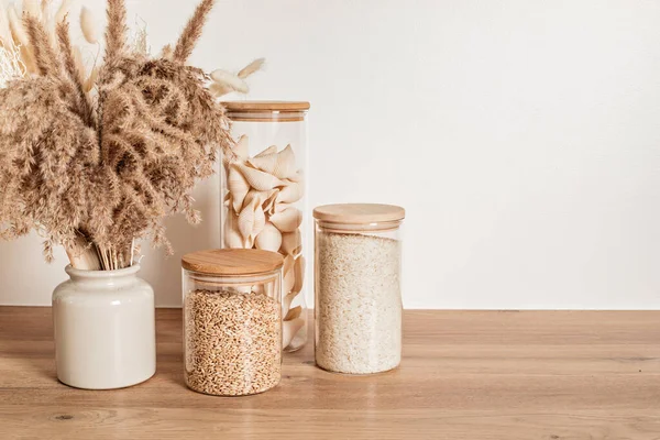 Assortment of grains, cereals and pasta in glass jars on wooden table. Zero waste kitchen storage — Stock Photo, Image