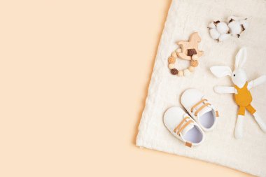 Bej arka planda cinsiyet ayrımcılığı olmayan bebek ayakkabıları ve aksesuarları.