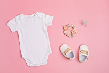 Çevre dostu bebek aksesuarlarıyla organik pamuktan yapılmış beyaz bebek tulumu.