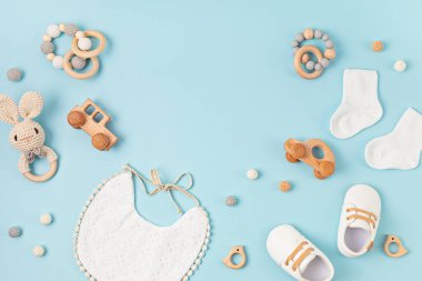 Pastel arka planda bebek ayakkabısı, önlük ve ip. Organik yeni doğan aksesuarlar