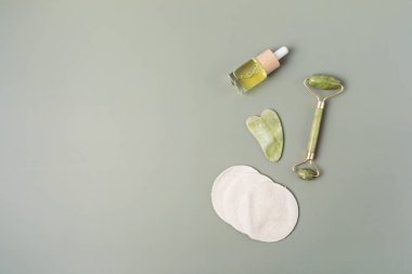 Yeşil yeşim yüzlü silindir, gua sha taşı, temel yağ. Doğal cilt bakımı