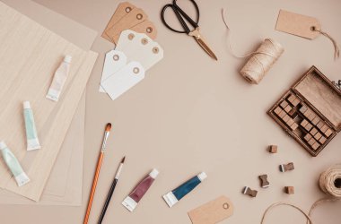 Pul alfabesi, boya, fırça, makas ve hediye etiketlerini bej arkaplan üzerine yapıştırın