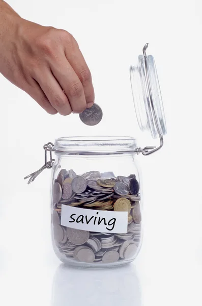 Saving concept: Hand putting a coin into jar Royalty Free Stock Photos