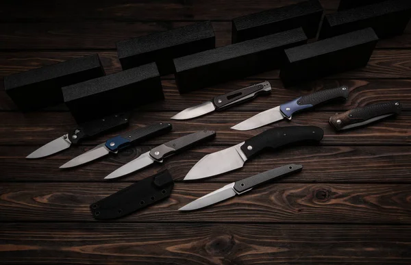 Folding knives on a wooden background. Pen knives on a dark brown background.