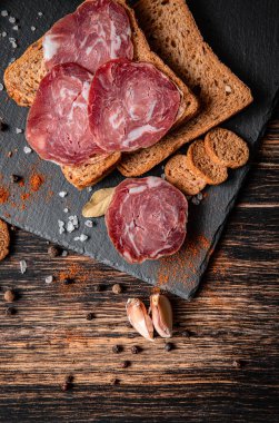 Tahta tabakta pişirilmiş et. Ahşap bir masada soğuk pirzola, ekmek ve baharatlar. Sandviç için ürünler..
