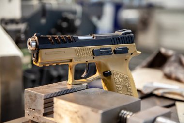 Bir atölyedeki çalışma masasında bej kabzalı modern bir tabanca. Silahların bakımı. Tabanca tamiri.