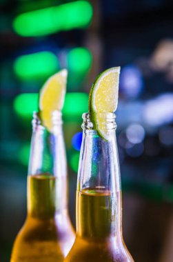 Bardaki şişelerde soğuk light bira. Limon parçaları şişelerin boyunlarını kapatır. Meksika birası.