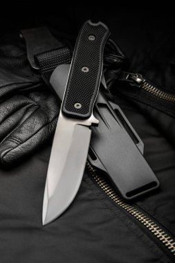 Kauçuk saplı modern bir avcı bıçağı ve arka planda plastik bir kılıf. Nefsi müdafaa ve hayatta kalmak için silahları hazırlayın..