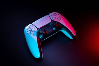 Kırmızı ve maviyle aydınlatılmış modern beyaz oyun sahası. Karanlık bir arkaplanda video oyunları ve e-sporlar için oyun denetleyici.