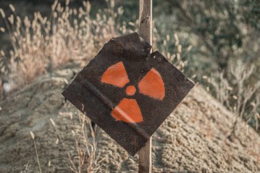 Paslı metal bir plakada radyasyon işareti. Tehlike uyarısı. Kıyamet sonrası işareti..