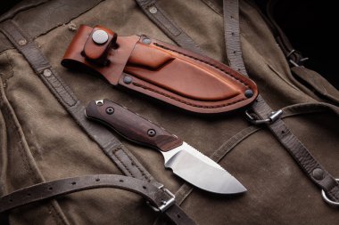 Tahta saplı bir av bıçağı ve haki rengi bir sırt çantasında deri bir çanta. Nefsi müdafaa ve hayatta kalma silahları..