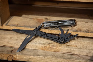 İki taktik çoklu alet, biri açık ve siyah, diğeri kapalı ve gümüş, ahşap tahtalar üzerinde..