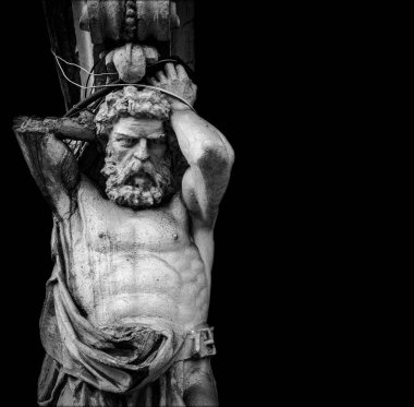 Yüklü bir Atlas heykelinin koyu siyah arkaplana karşı yüksek kontrastlı siyah ve beyaz yakın çekimi