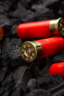 Koyu, pürüzlü kömür arka planında 12 kalibrelik üç adet av tüfeği fişeği yakın plan..