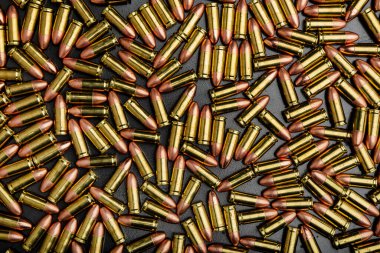 Dağınık altın ve bakır tabanca fişeklerinin tam kare, tepeden görünüşü.