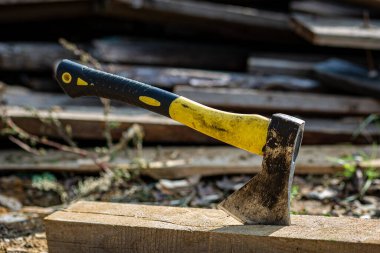 Tahta bir kirişin üzerinde duran sarı ve siyah saplı bir balta kullanılmış..