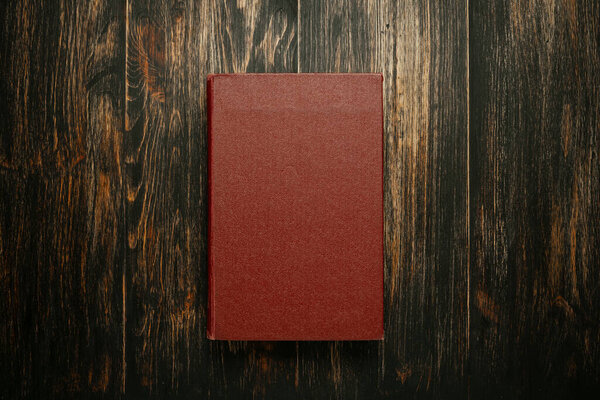 Blank burgundy book cover centered on a rich, dark, rustic wooden background.