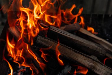 Yoğun turuncu alevler, koyu metal ızgarada odun yakar..