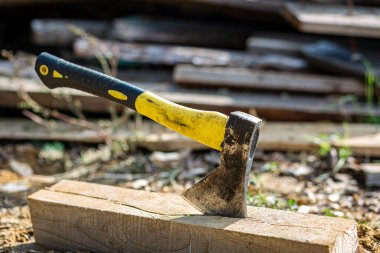 Tahta bir kirişin üzerinde duran sarı ve siyah saplı bir balta kullanılmış..