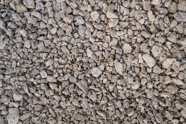 Kuru, pürüzlü, açık gri ve bej rengi ezilmiş kaya veya inşaat çakıllarının yakın çekim dokusu.