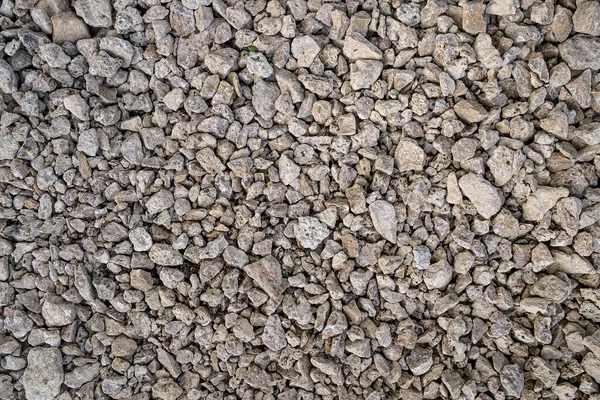 Kuru, pürüzlü, açık gri ve bej rengi ezilmiş kaya veya inşaat çakıllarının yakın çekim dokusu.